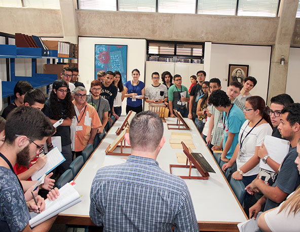 Foto de personas durante una visita guiada en la sala de consulta observando documentos antiguos